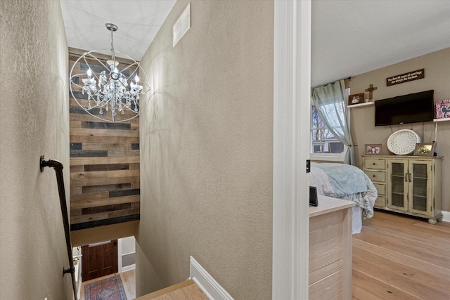 stairway with hardwood / wood-style floors and a chandelier