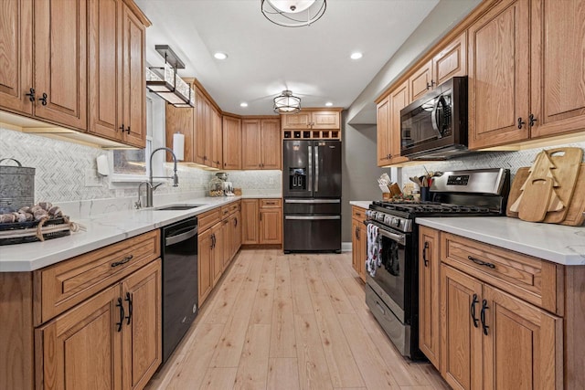 kitchen featuring sink, backsplash, black appliances, and light hardwood / wood-style floors