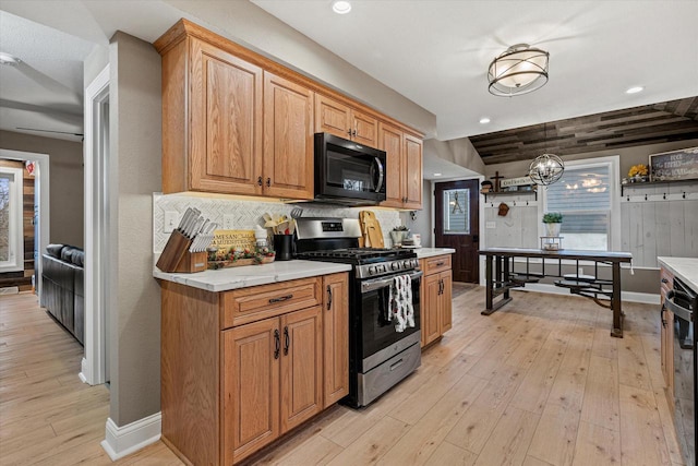 kitchen featuring hanging light fixtures, stainless steel range with gas stovetop, backsplash, and light hardwood / wood-style floors