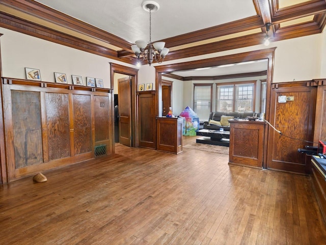 interior space with hardwood / wood-style flooring, ornamental molding, beam ceiling, and a notable chandelier