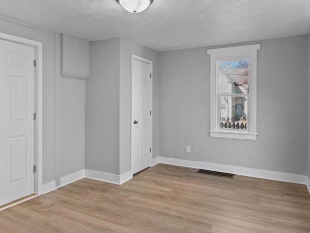 unfurnished room with light hardwood / wood-style floors and a textured ceiling