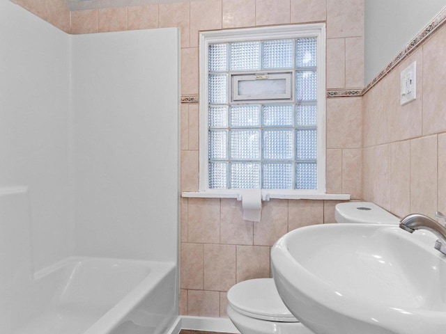 bathroom featuring toilet, sink, and tile walls