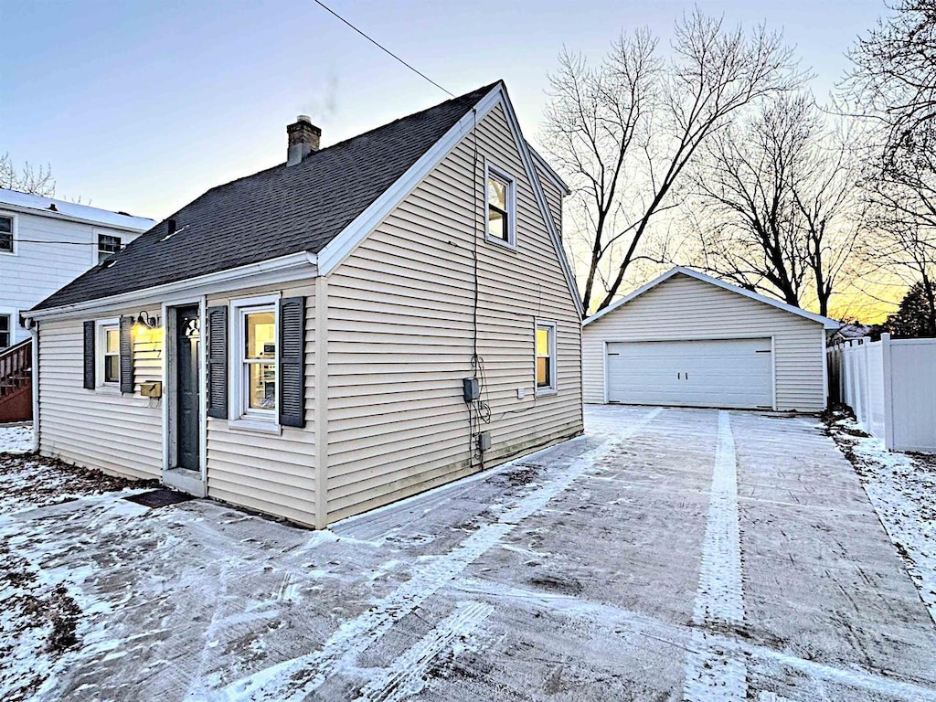 view of snowy exterior with a garage and an outdoor structure