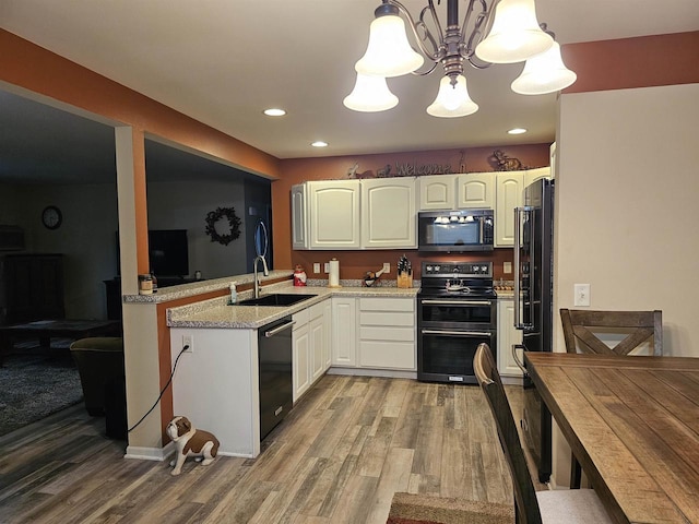 kitchen featuring sink, white cabinetry, hanging light fixtures, hardwood / wood-style floors, and black appliances