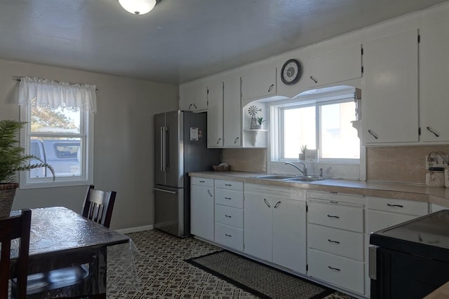 kitchen with stainless steel fridge, sink, decorative backsplash, and white cabinets