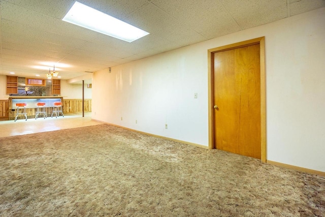 basement featuring an inviting chandelier, carpet, and a drop ceiling