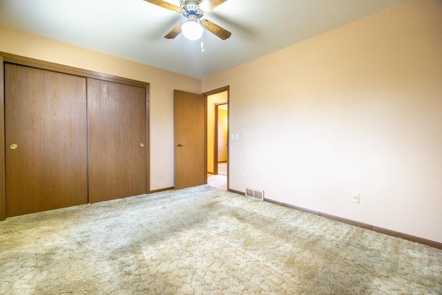 unfurnished bedroom with light colored carpet, a closet, and ceiling fan