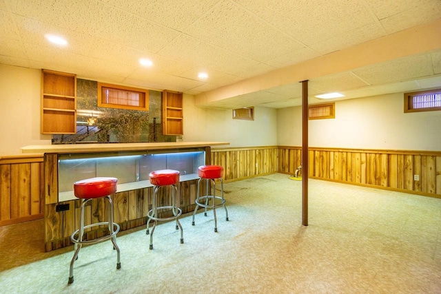 bar with a paneled ceiling and wood walls