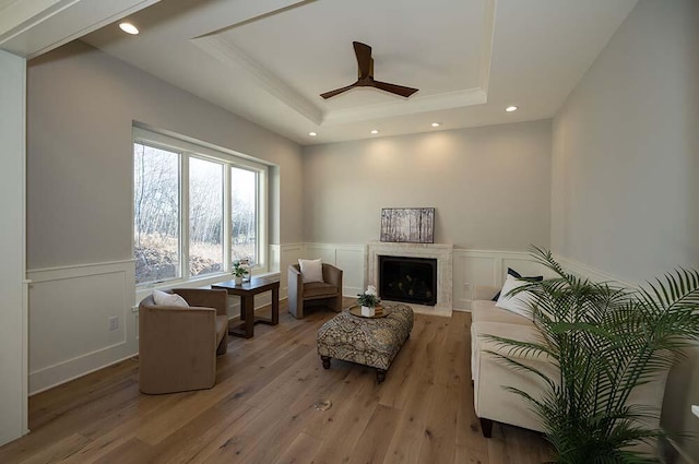 living room with ceiling fan, a tray ceiling, and light hardwood / wood-style floors