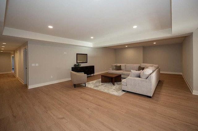 living room with a tray ceiling and light hardwood / wood-style floors