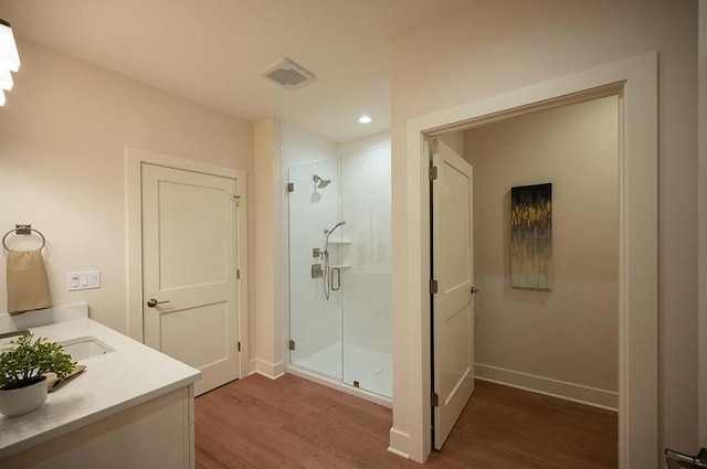 bathroom featuring hardwood / wood-style flooring, vanity, and a shower with door