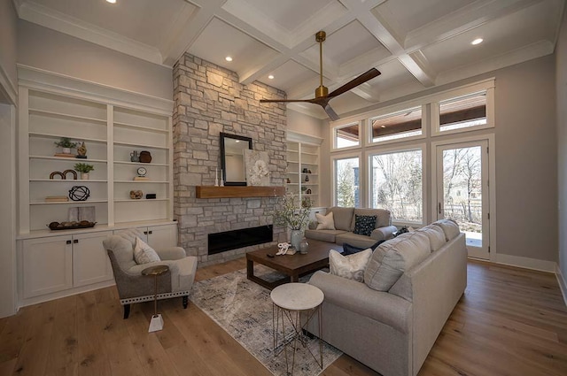 living room featuring light hardwood / wood-style flooring, beam ceiling, coffered ceiling, a fireplace, and built in shelves