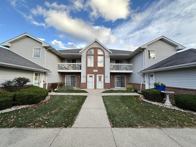 view of property with a front yard and a balcony