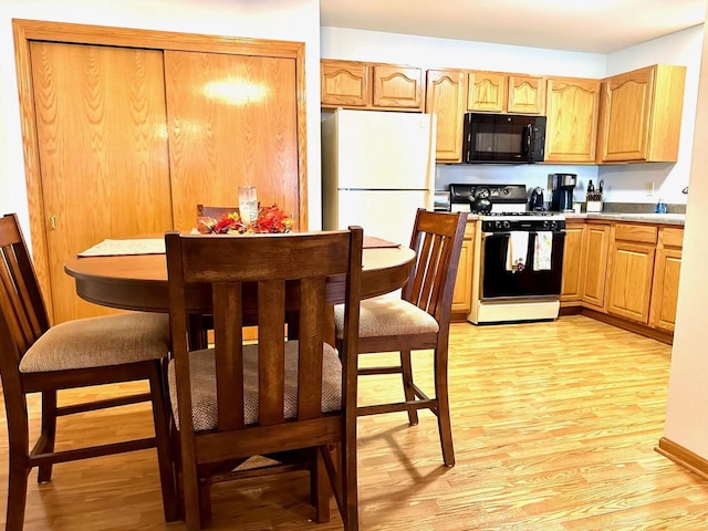 kitchen with white refrigerator, light hardwood / wood-style floors, and gas stove