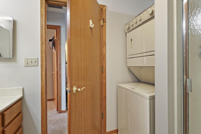 laundry area with stacked washer / drying machine and light carpet