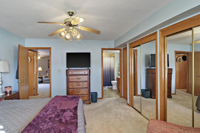 carpeted bedroom featuring ceiling fan, ensuite bath, and multiple closets