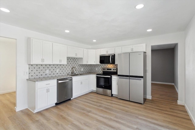 kitchen featuring appliances with stainless steel finishes, sink, white cabinets, backsplash, and light hardwood / wood-style flooring