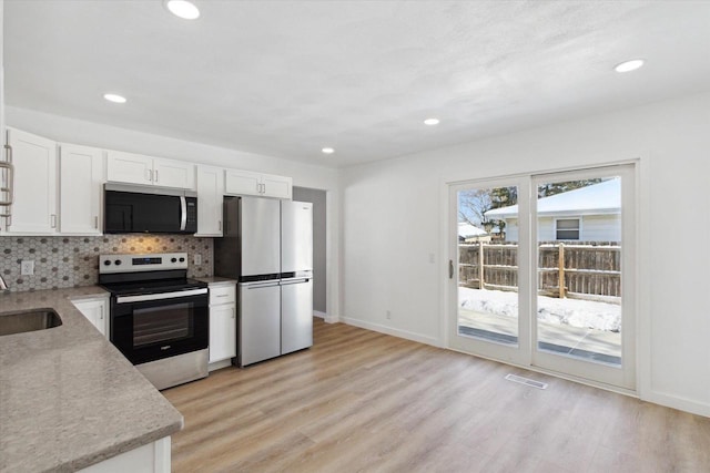 kitchen with white cabinetry, appliances with stainless steel finishes, sink, and light hardwood / wood-style flooring