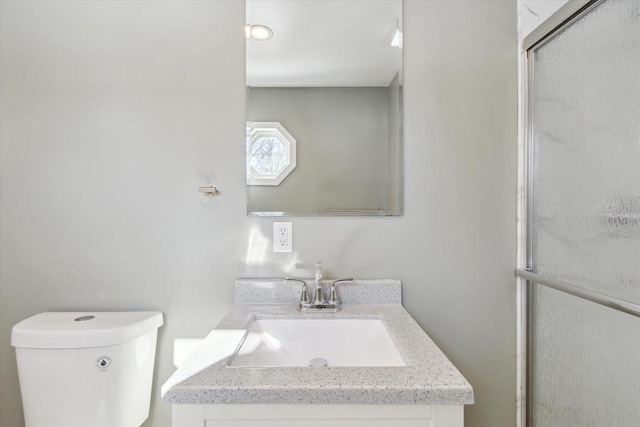 bathroom with vanity, toilet, and a shower with door