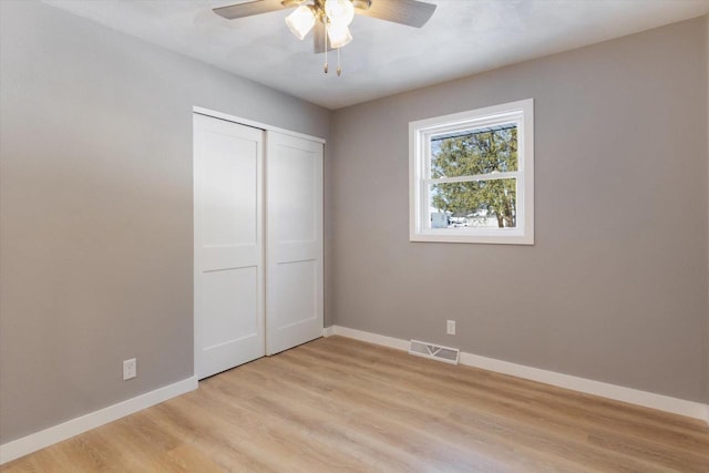 unfurnished bedroom featuring light hardwood / wood-style floors, ceiling fan, and a closet