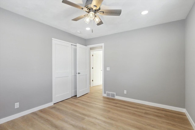 unfurnished bedroom with light wood-type flooring, ceiling fan, and a closet