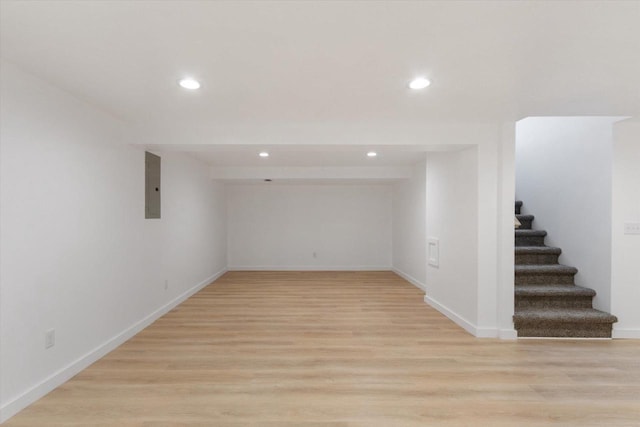 basement with light hardwood / wood-style floors and electric panel