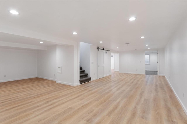 basement with light hardwood / wood-style flooring and a barn door