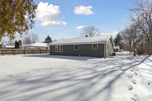 snow covered rear of property featuring central AC unit