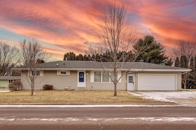 ranch-style house with a garage and a lawn