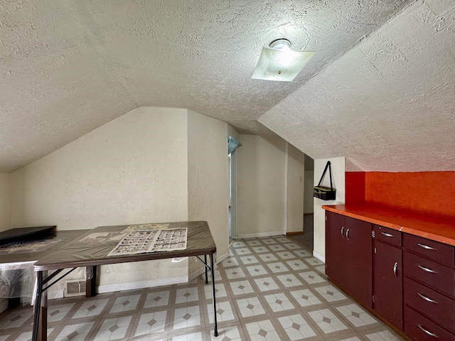 additional living space featuring vaulted ceiling and a textured ceiling