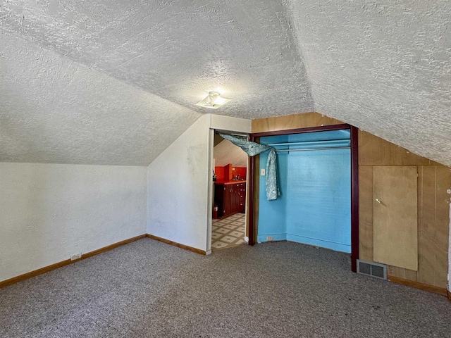 bonus room with carpet floors, vaulted ceiling, and a textured ceiling