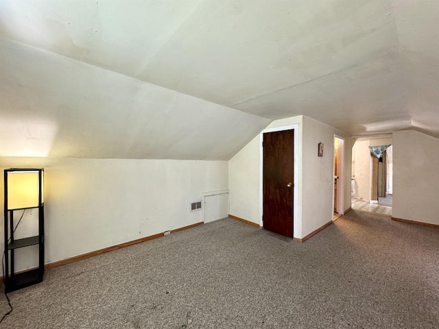 additional living space featuring vaulted ceiling and carpet flooring