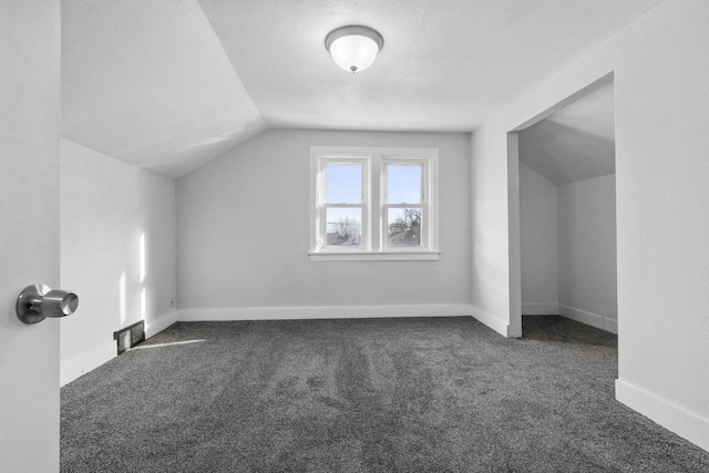 bonus room with lofted ceiling, dark carpet, and a textured ceiling