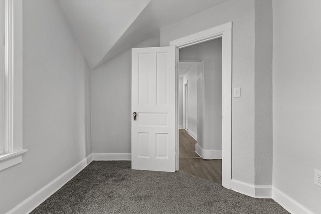 additional living space with vaulted ceiling and dark colored carpet