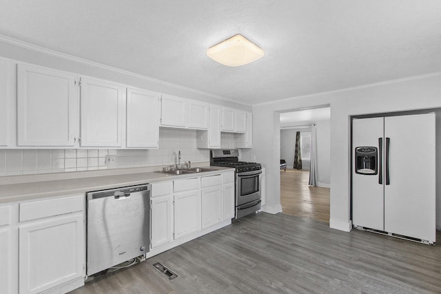 kitchen with sink, white cabinetry, tasteful backsplash, wood-type flooring, and appliances with stainless steel finishes