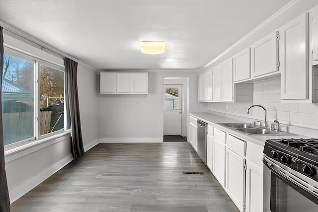 kitchen with sink, stainless steel appliances, tasteful backsplash, a healthy amount of sunlight, and white cabinets