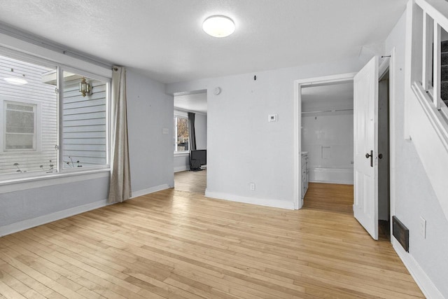 unfurnished bedroom with a closet, a textured ceiling, and light hardwood / wood-style flooring