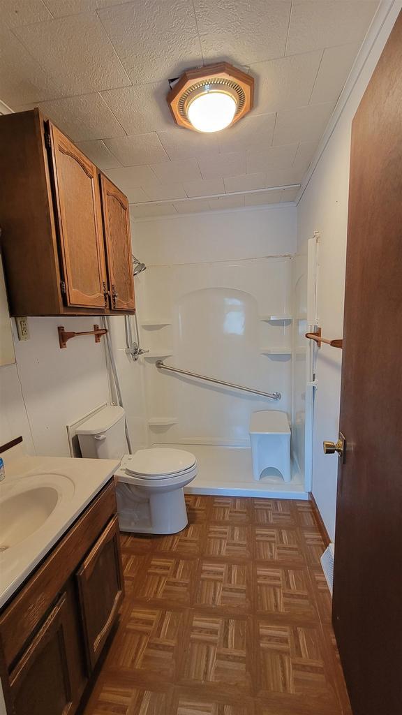 full bathroom featuring vanity, parquet flooring, bathtub / shower combination, and toilet