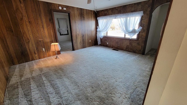 carpeted spare room with wooden walls