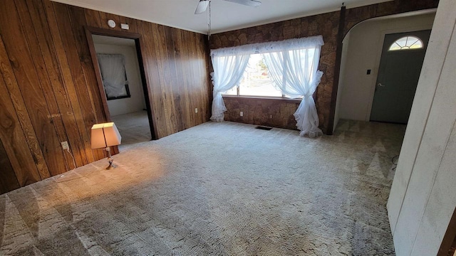 interior space with carpet and wood walls