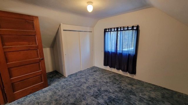 unfurnished bedroom featuring vaulted ceiling, a closet, and dark colored carpet