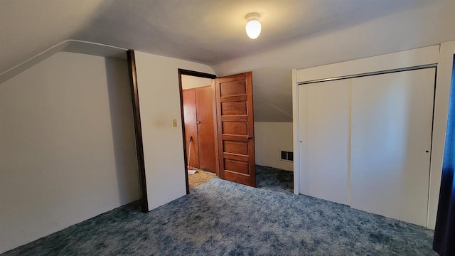 unfurnished bedroom featuring dark colored carpet, vaulted ceiling, and a closet