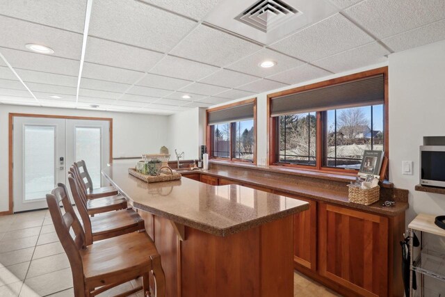2743 Brooks Ridge Dr, Sun Prairie, WI 53590 - kitchen featuring french doors, a breakfast bar, sink, light tile patterned floors, and a drop ceiling