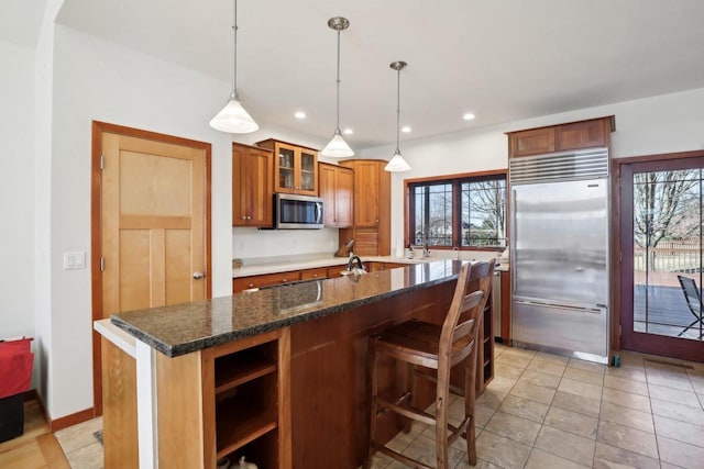 2743 Brooks Ridge Dr, Sun Prairie, WI 53590 - kitchen featuring dark stone countertops, hanging light fixtures, stainless steel appliances, a kitchen breakfast bar, and a kitchen island