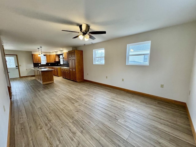 unfurnished living room with sink, ceiling fan, and light hardwood / wood-style flooring