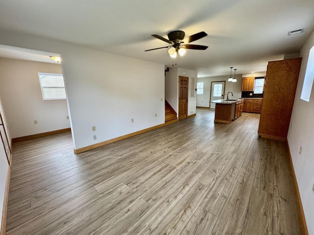 unfurnished living room with ceiling fan, sink, and light hardwood / wood-style floors