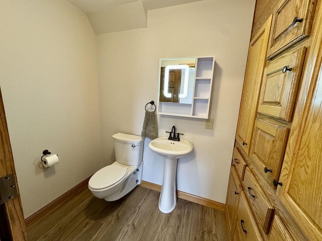 bathroom featuring wood-type flooring, toilet, and vaulted ceiling