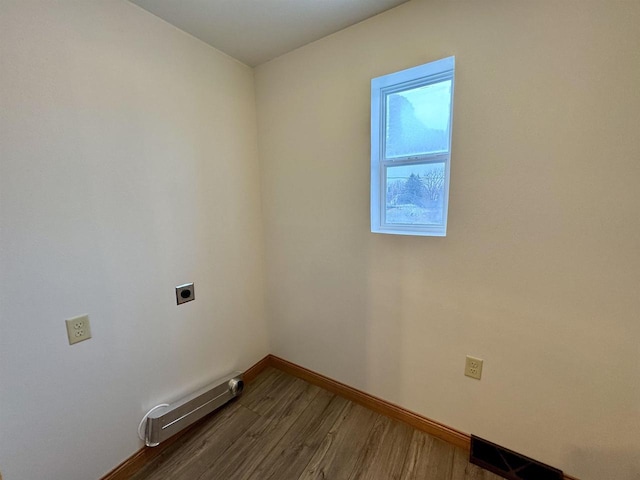 laundry area featuring electric dryer hookup, hardwood / wood-style floors, and a baseboard heating unit