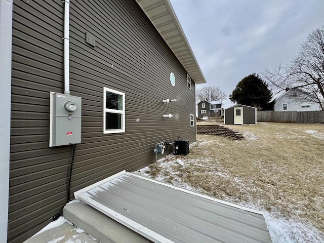 view of side of home with central AC unit and a shed