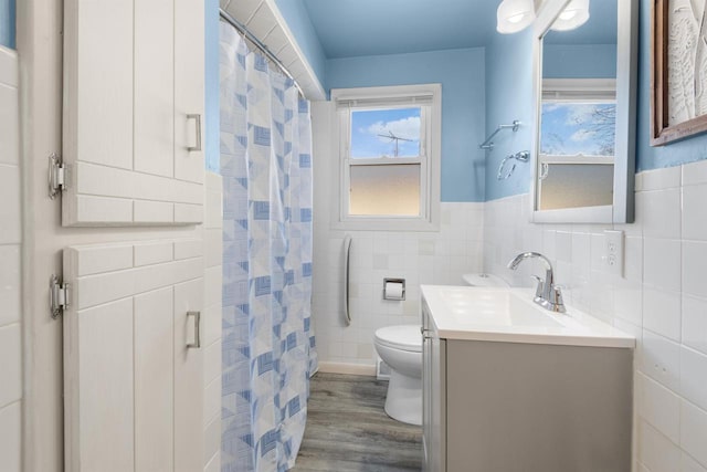 bathroom with walk in shower, toilet, wood-type flooring, tile walls, and vanity